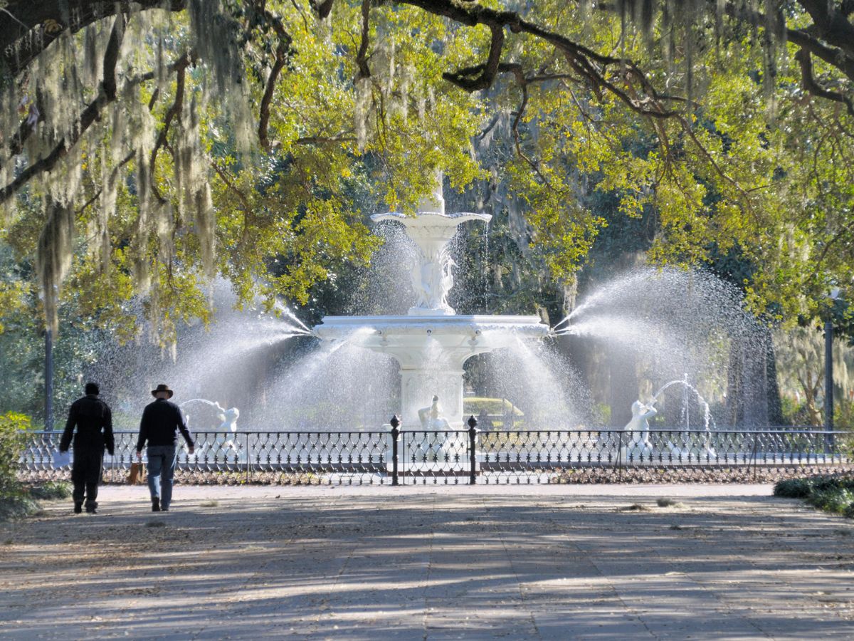 Two people walking toward the fountain in Forsyth Park